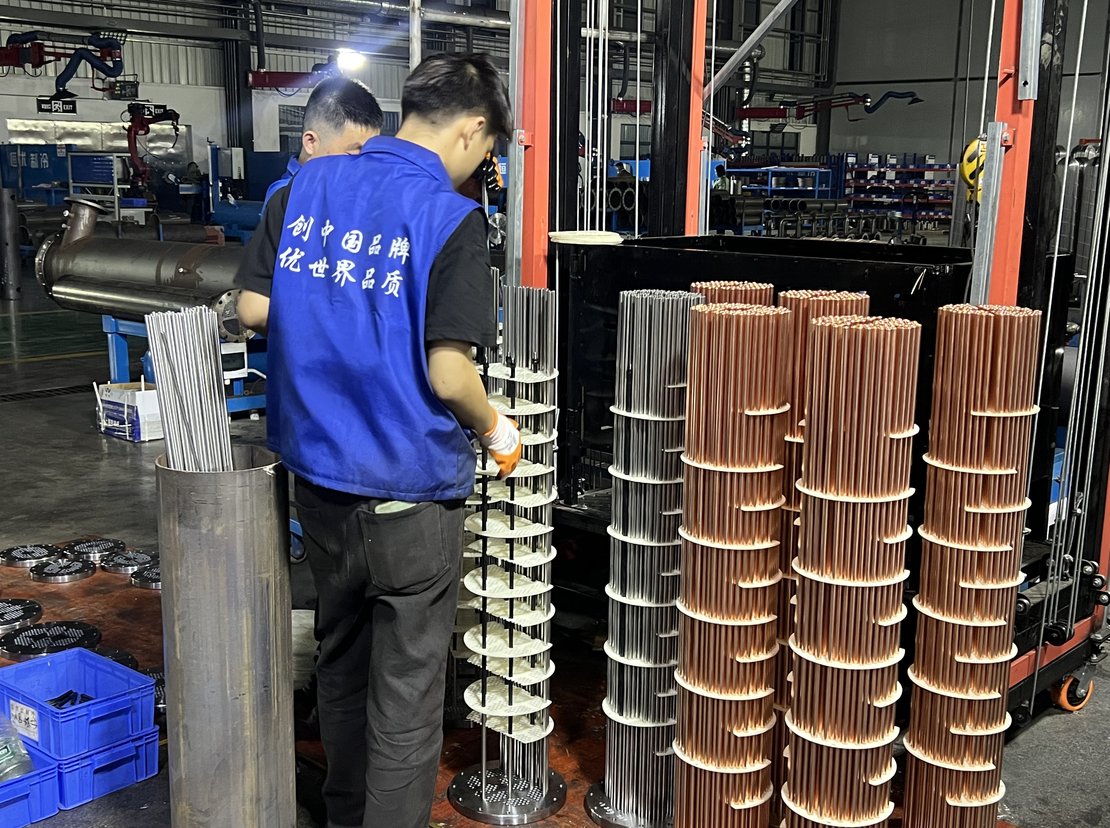 Operator assembling copper tubes and ferrules into a drilled tube sheet